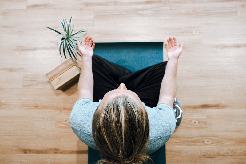 birdseye view of a woman sat on a yoga mat practicing meditation