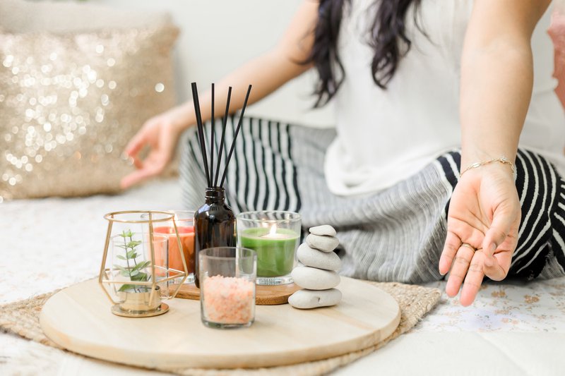 image of a person sitting in lotus position with scent and candles meditating